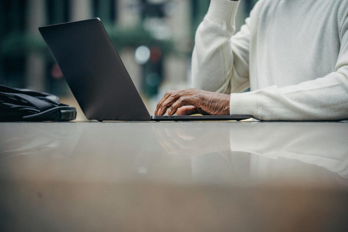 unrecognizable african american man using laptop in street cafe