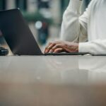 unrecognizable african american man using laptop in street cafe